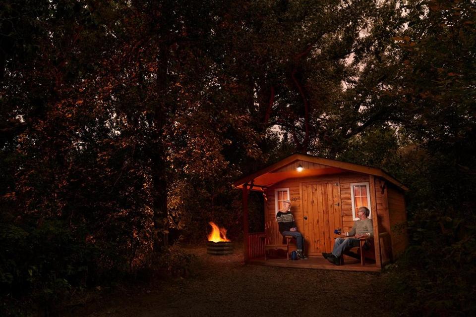 a couple of people sitting in a shed with a fire at 11 Bridges Campground and Cabin Park in Rosedale