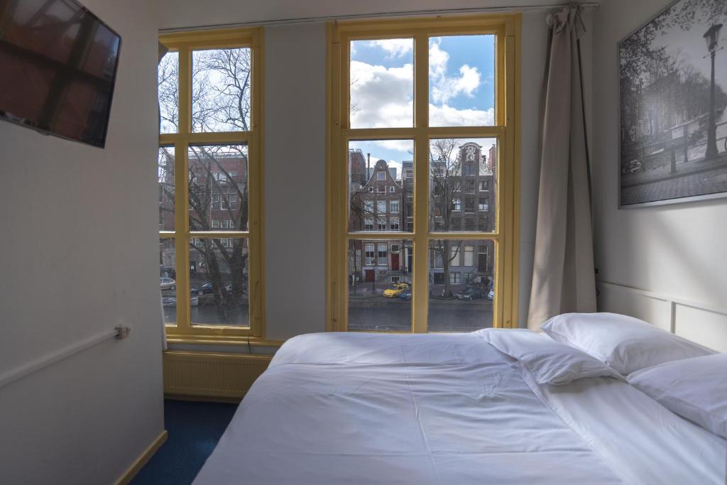 a bedroom with a bed and two windows at Hotel Hoksbergen in Amsterdam