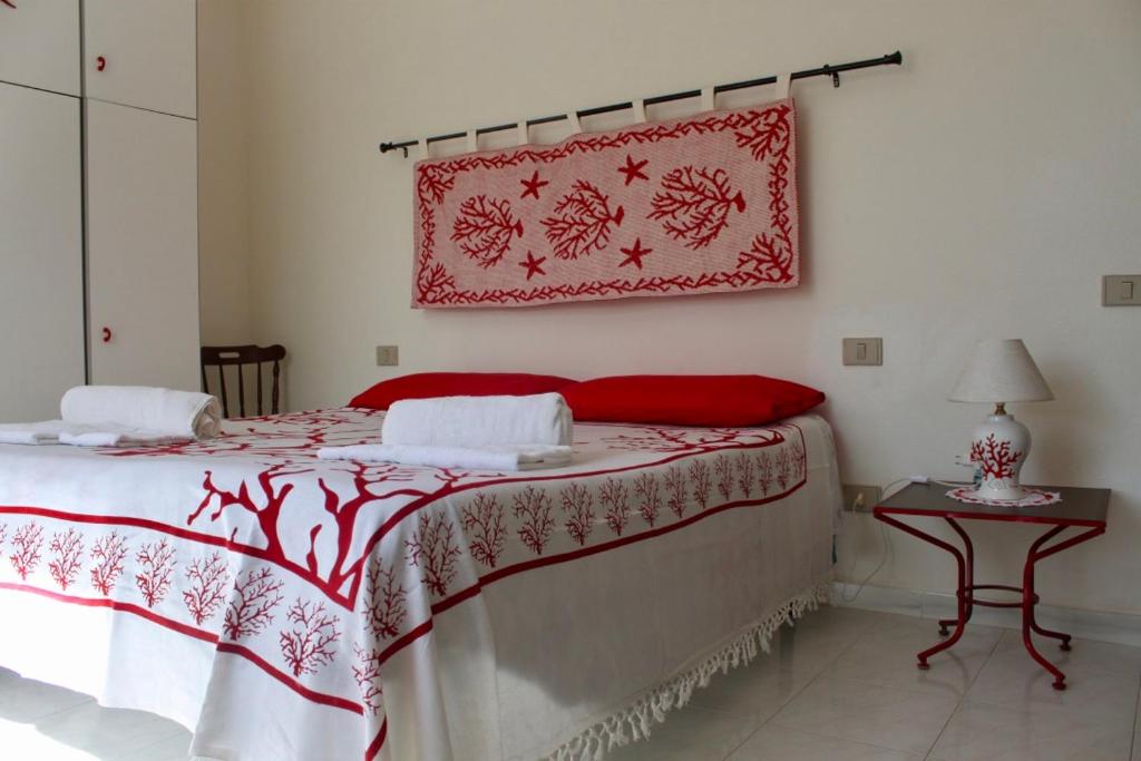 - une chambre dotée d'un lit avec une couverture rouge et blanche dans l'établissement La Lampara, à Stintino