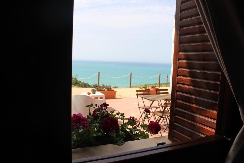 a view of the beach from a window with flowers at B&B La Torre in Realmonte