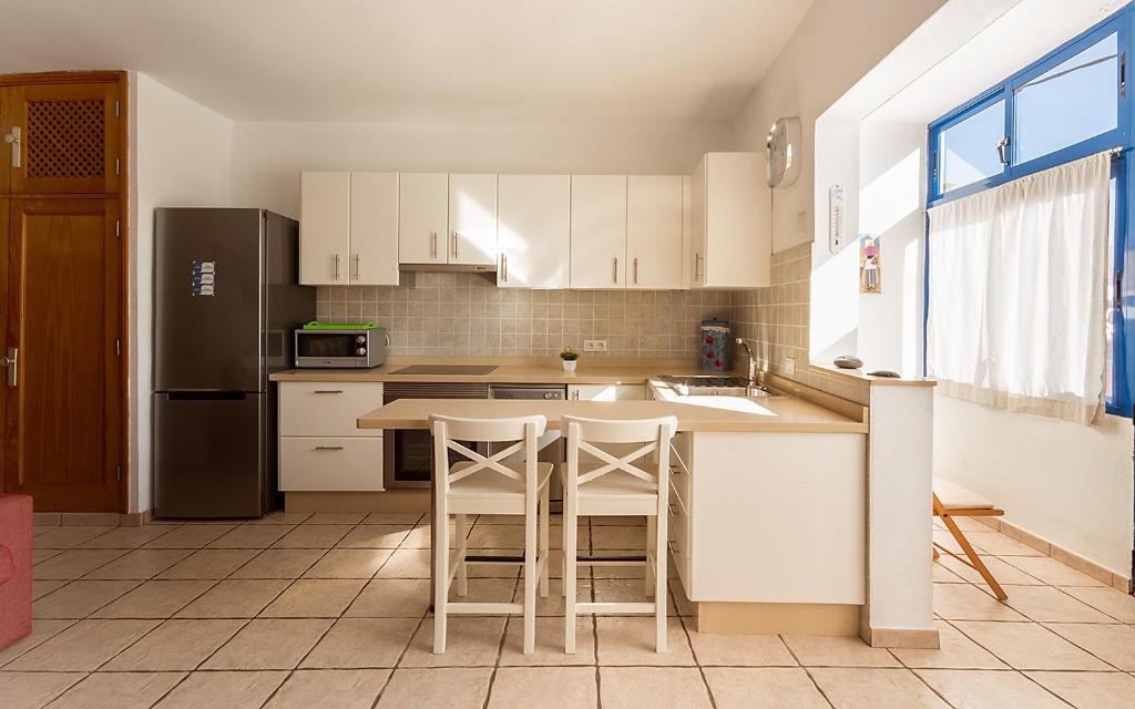 a kitchen with white cabinets and a table and a refrigerator at Casa Maralba Famara in Famara