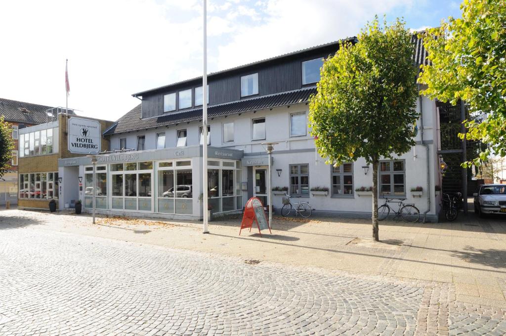 a building on a street with a tree in front of it at Hotel Vildbjerg in Vildbjerg