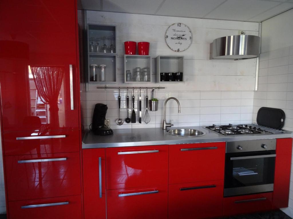 uma cozinha vermelha com um lavatório e um fogão em Het Pronkje em Renesse