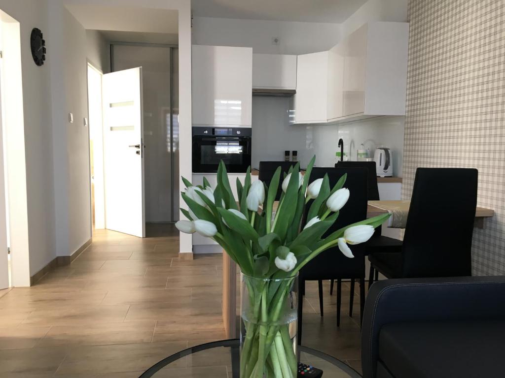 un jarrón de flores blancas sentado en una mesa de cristal en Apartamenty AP 8, en Częstochowa