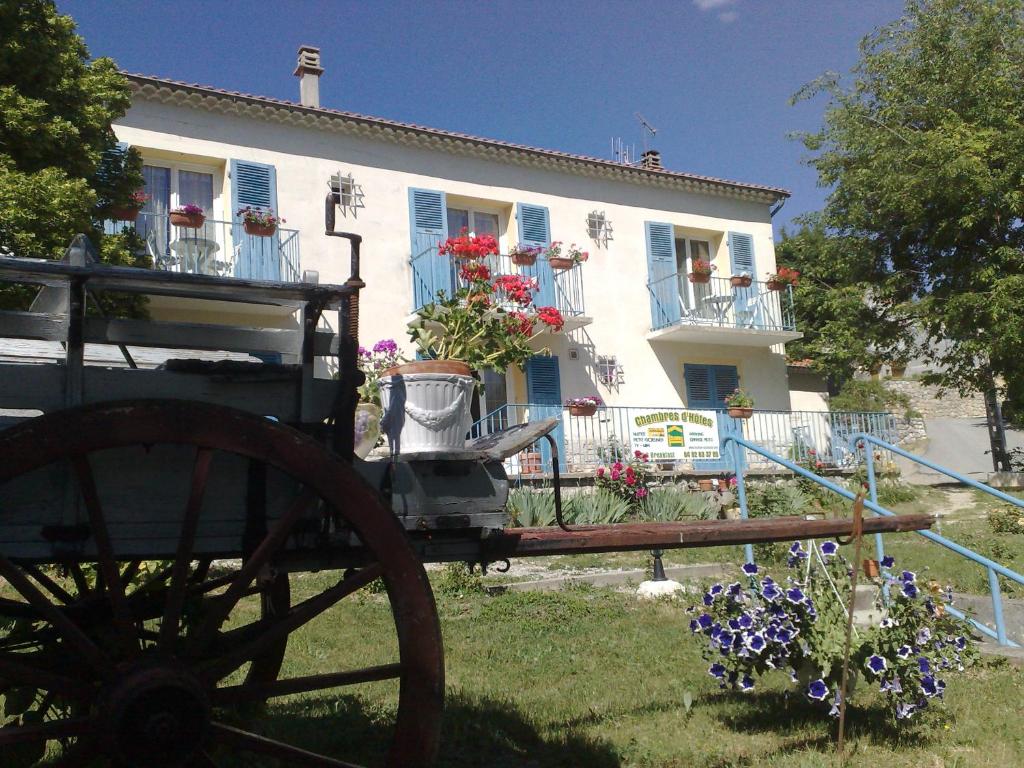 une vieille charrette devant une maison fleurie dans l'établissement Aqui Sian Ben, à Castellane