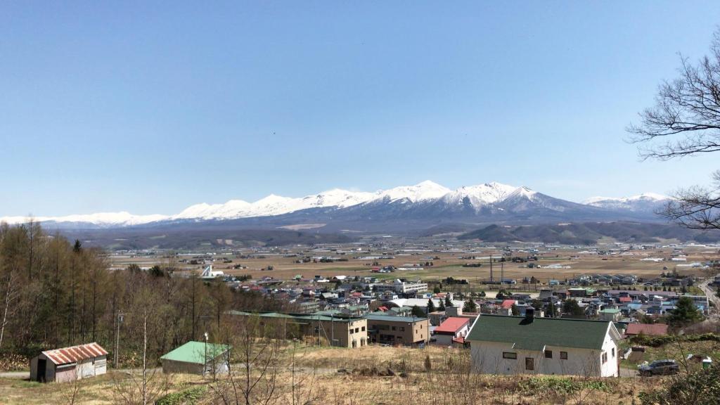Pension Yamasan في Nakafurano: مدينة صغيرة بها جبال مغطاة بالثلوج في الخلفية
