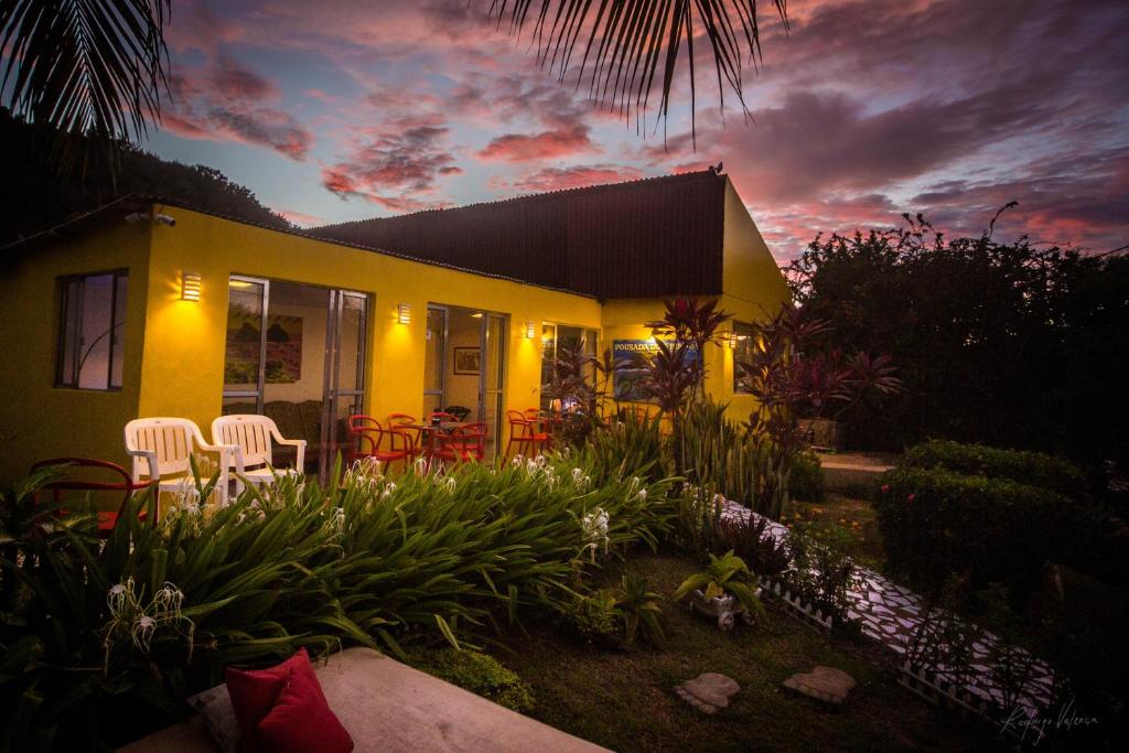 a yellow house with chairs and tables in a yard at Pousada Dois Irmãos in Fernando de Noronha