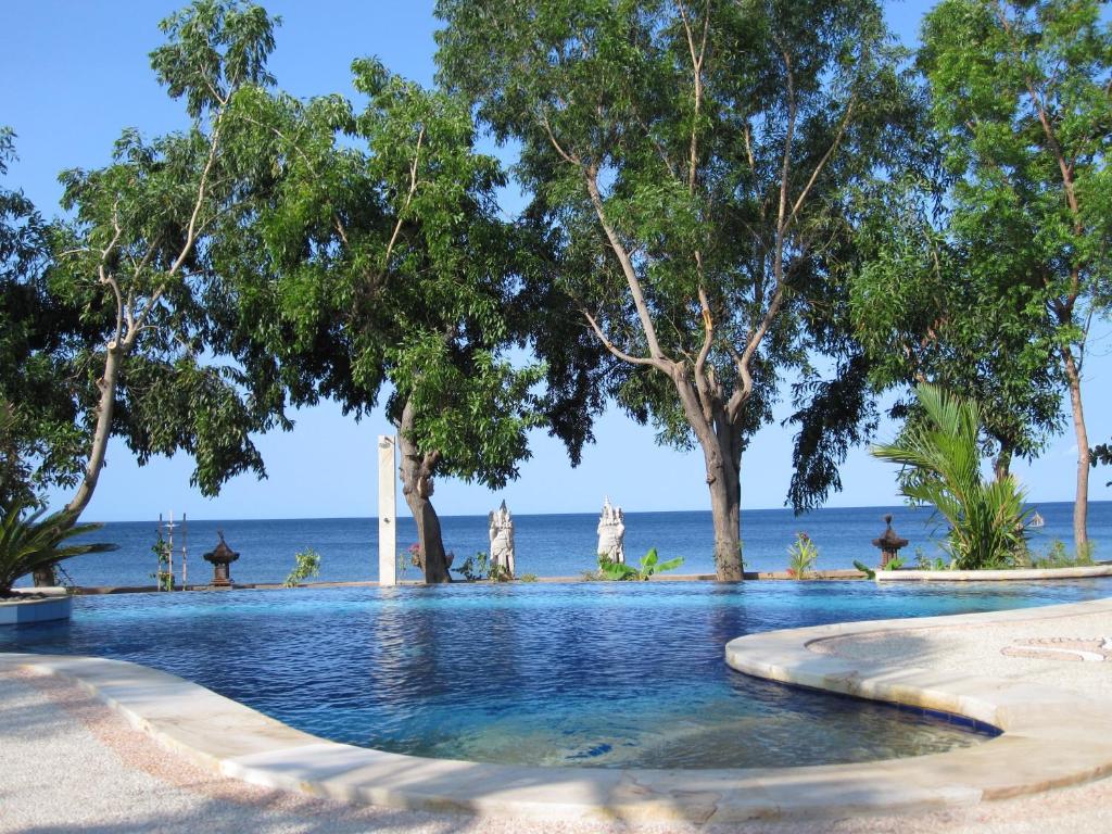 une piscine avec des arbres et l'océan en arrière-plan dans l'établissement Bali Dream House, à Amed