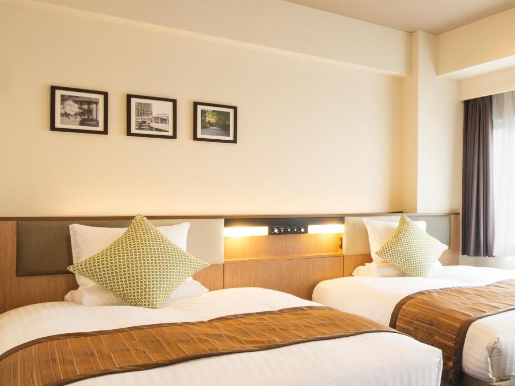 a hotel room with two beds and two pictures on the wall at Hotel Mystays Gotanda Station in Tokyo