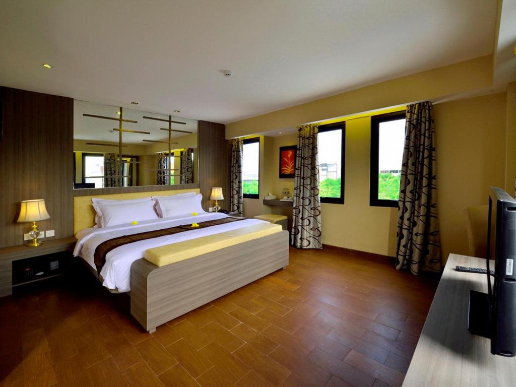 1 dormitorio con 1 cama grande y espejo grande en Serela Kuta by KAGUM Hotels, en Kuta