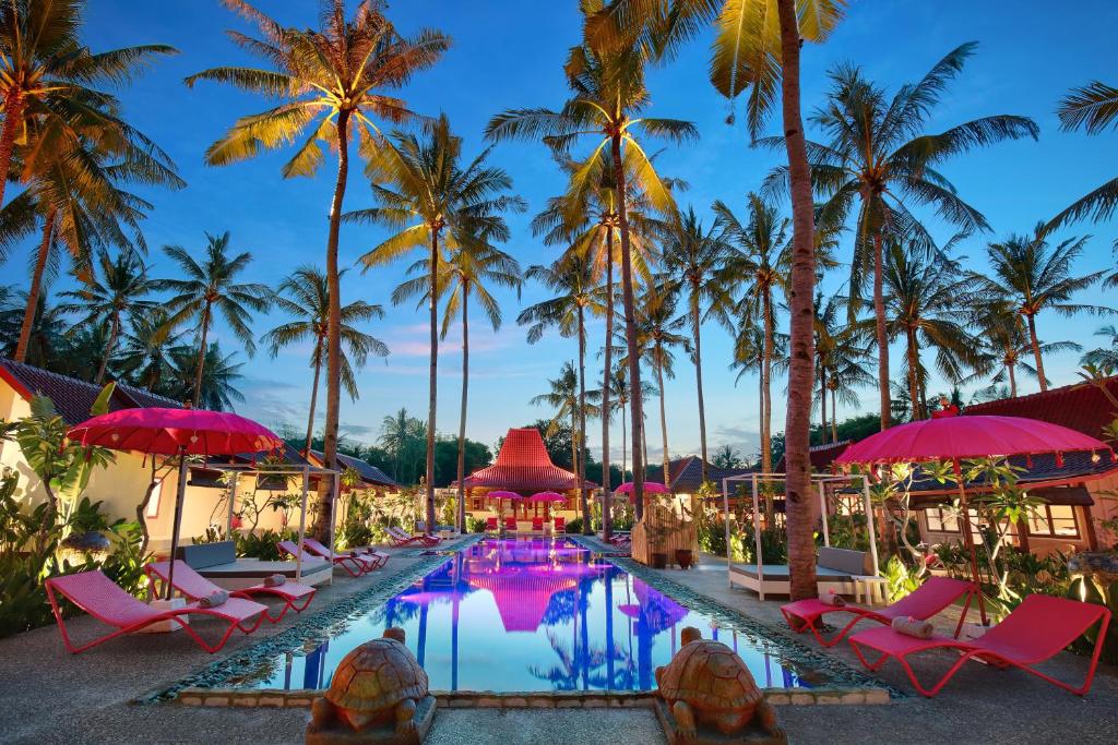 a pool at the resort with pink chairs and palm trees at PinkCoco Gili Air - Constant Surprises - for Cool Adults Only in Gili Air