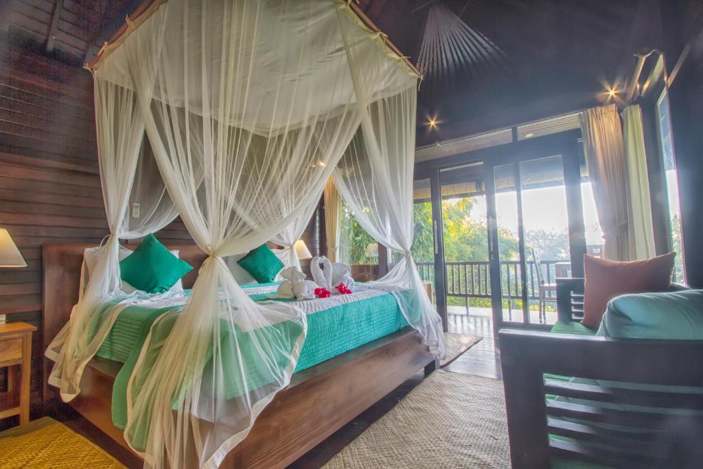 1 dormitorio con cama con dosel y cortinas en Villa Wedang, en Tegalalang