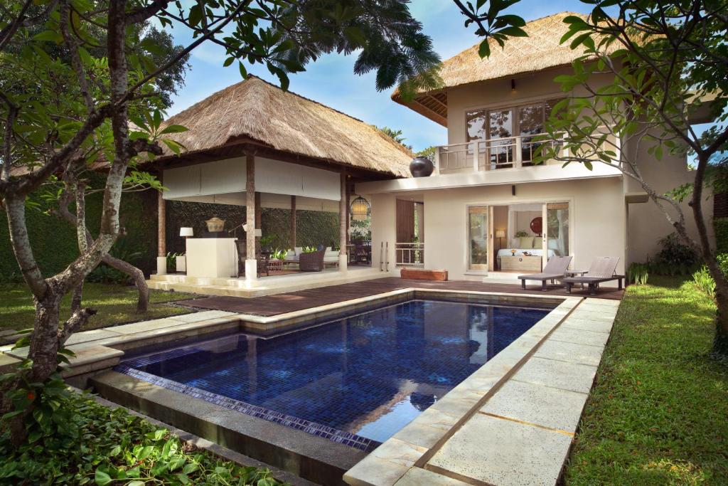 a villa with a swimming pool in front of a house at Kayumanis Sanur Private Villa and Spa in Sanur