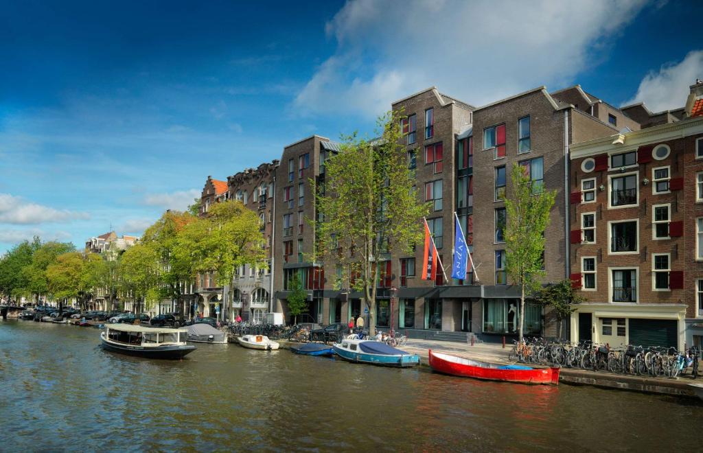 een groep boten in een rivier naast gebouwen bij Andaz Amsterdam, Prinsengracht, By Hyatt in Amsterdam