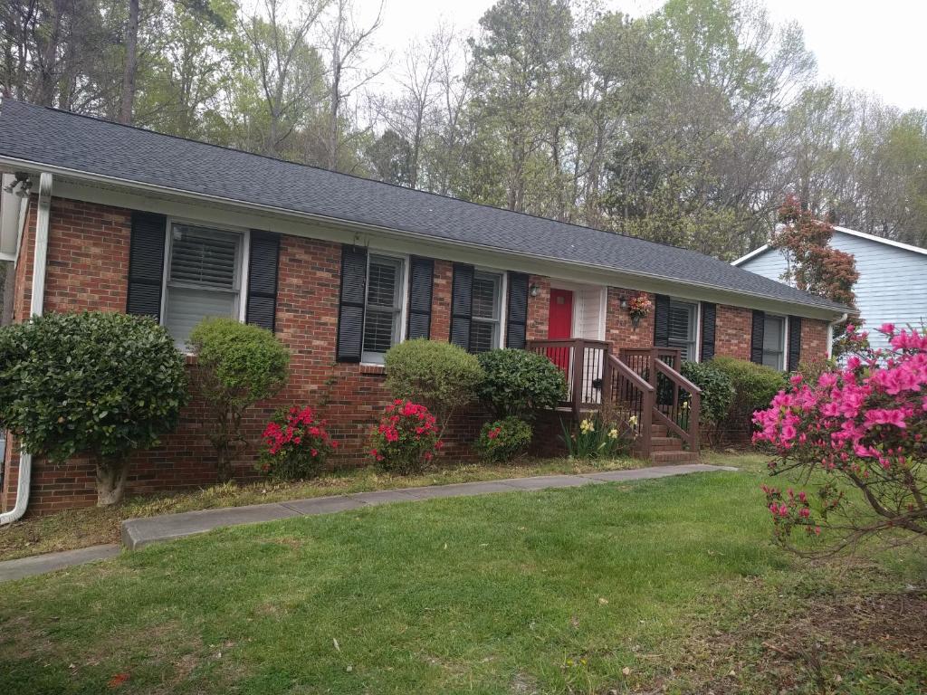 een bakstenen huis met roze bloemen in de tuin bij University City Guest House in Charlotte