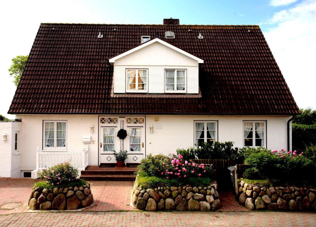 una casa blanca con flores delante en Haus Elvi Fuchs an den alten Salzwiesen en Westerland