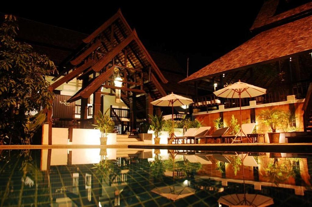 a resort with a swimming pool with tables and umbrellas at Rainforest ChiangMai Hotel in Chiang Mai