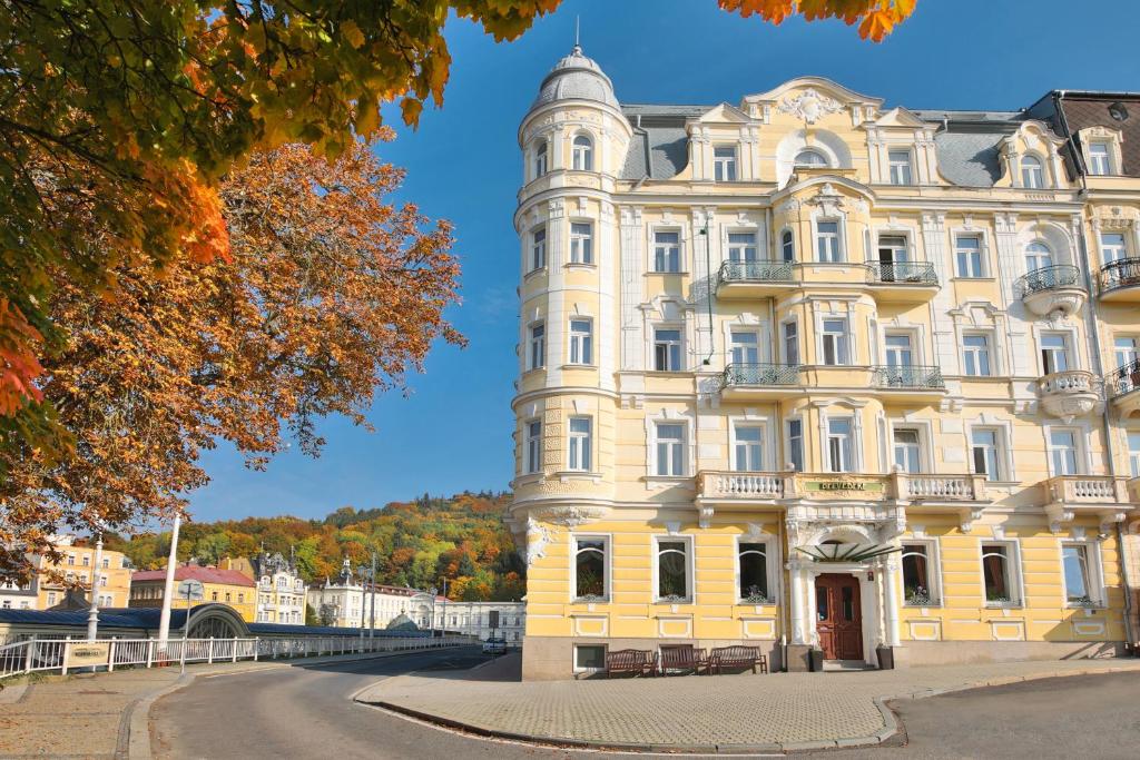 ein großes gelbes Gebäude mit einem Uhrturm in der Unterkunft Belvedere Wellness Hotel in Marienbad