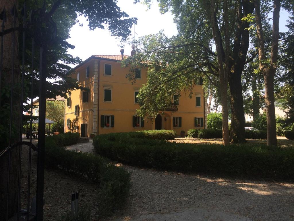 un edificio amarillo con árboles delante de él en Villa Gioia en San Giorgio di Piano