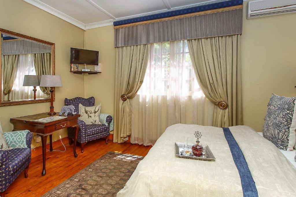 a hotel room with a bed and a table and a desk at Riverside Guest Lodge in Oudtshoorn