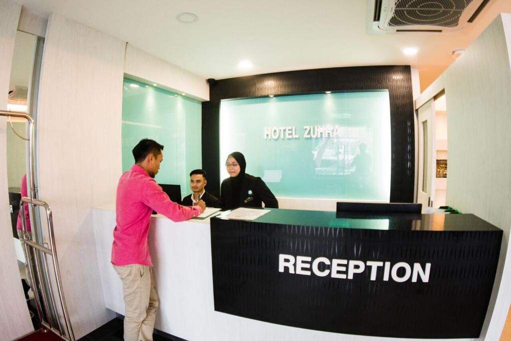 a man standing at a reception desk in a room at Hotel Zuhra in Sibu