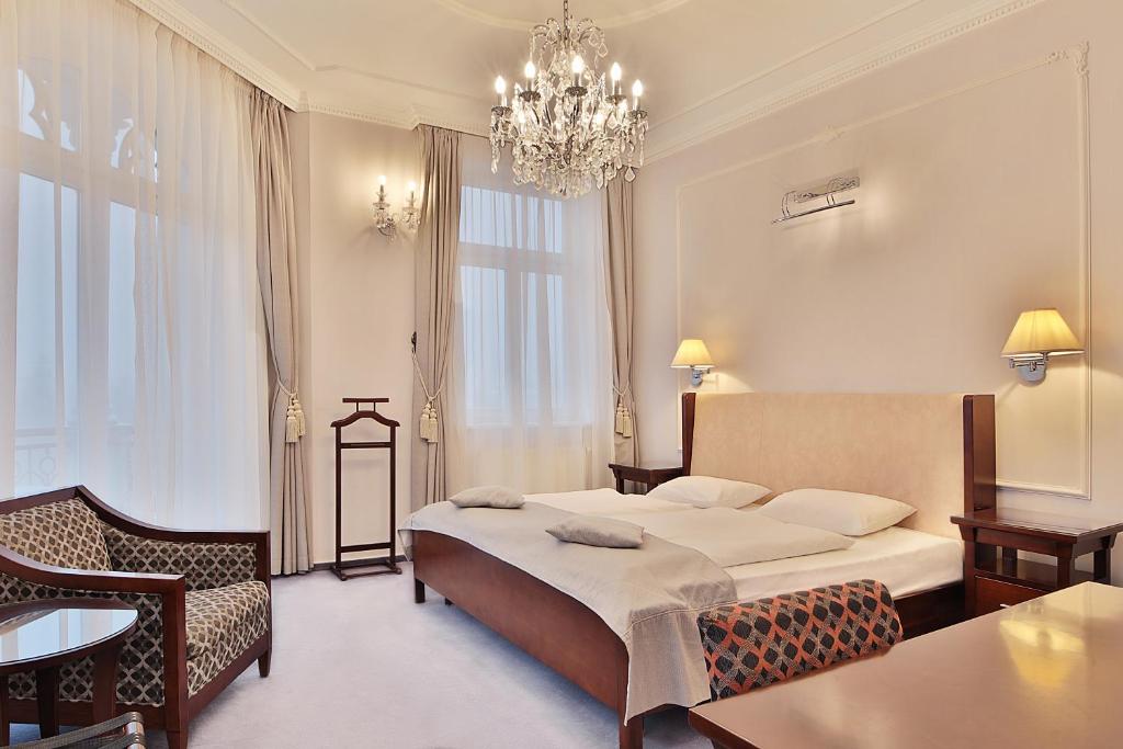 um quarto de hotel com uma cama e um lustre em Sun Palace Wellness Hotel em Mariánské Lázně