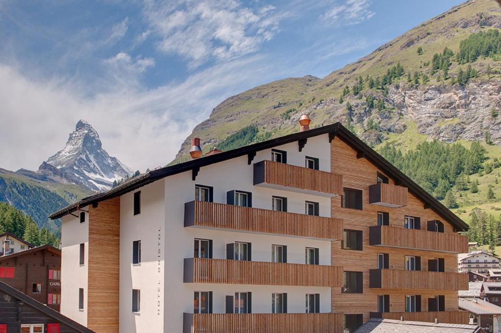 
a large building with a view of a mountain range at Hotel Bristol in Zermatt
