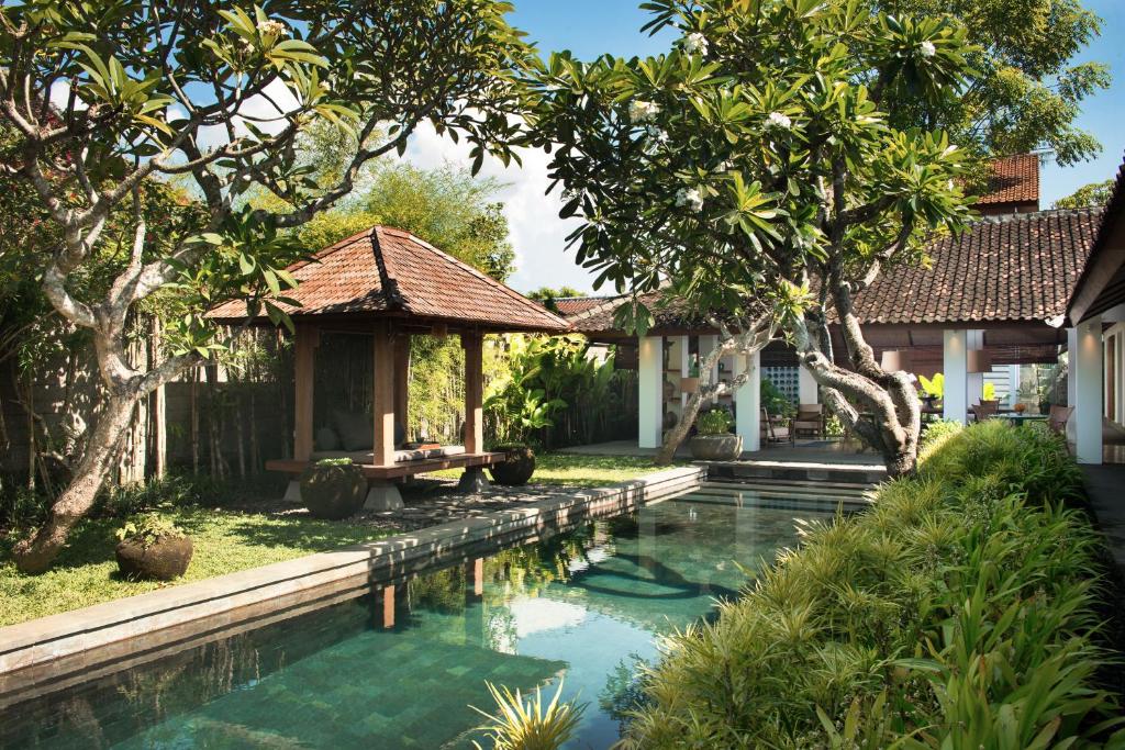 a swimming pool in front of a house with trees at Atelier TE Designer Guesthouse in Sanur