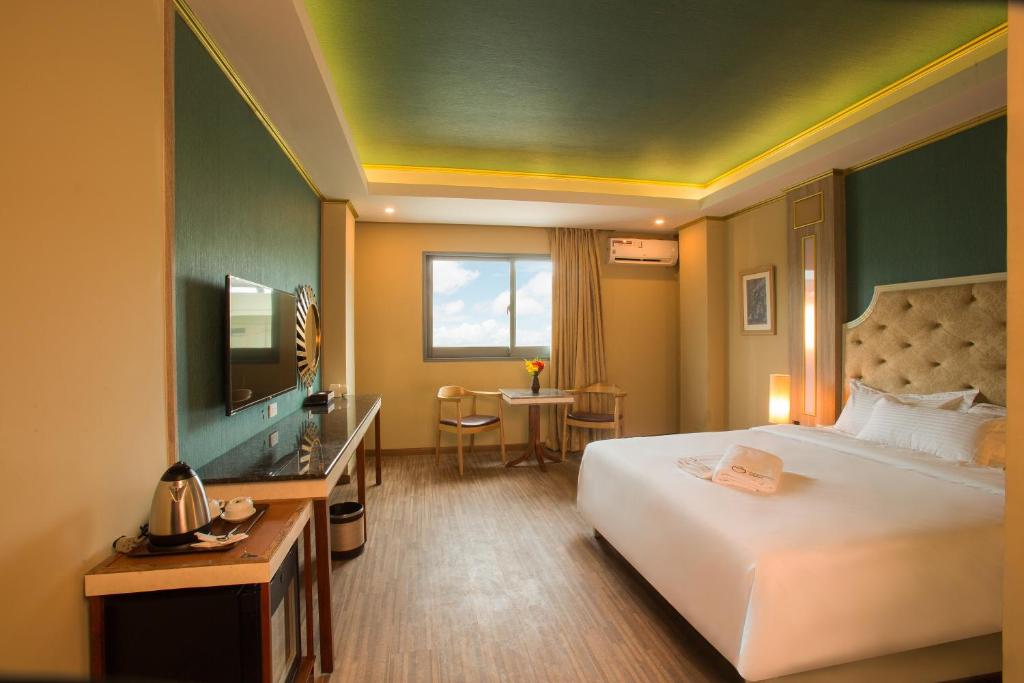 Habitación de hotel con cama, escritorio y TV. en Appleton Boutique Hotel Mactan Cebu en Isla de Mactán