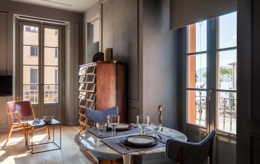 a dining room with a table and chairs and windows at Suites Menaggio in Menaggio