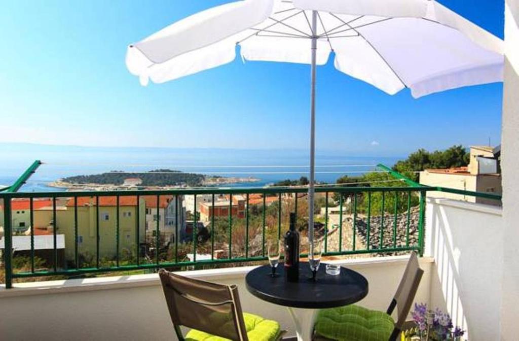 a table and chairs with an umbrella on a balcony at Kuća za odmor Batinić in Makarska