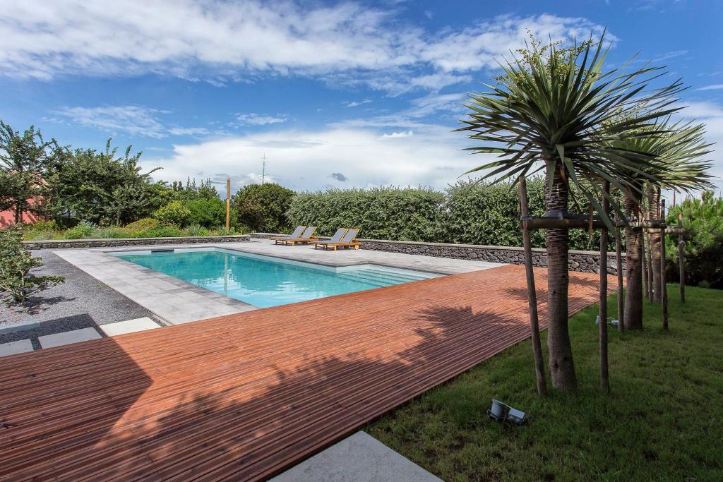 una piscina con terraza de madera junto a una palmera en Quinta dos Peixes Falantes, en Ribeira Grande