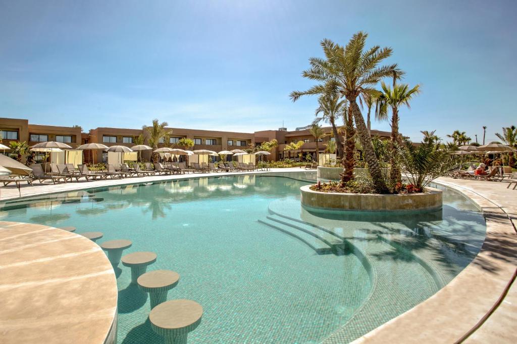 una piscina en un complejo con sillas y una palmera en Be Live Collection Marrakech Adults Only All inclusive en Marrakech