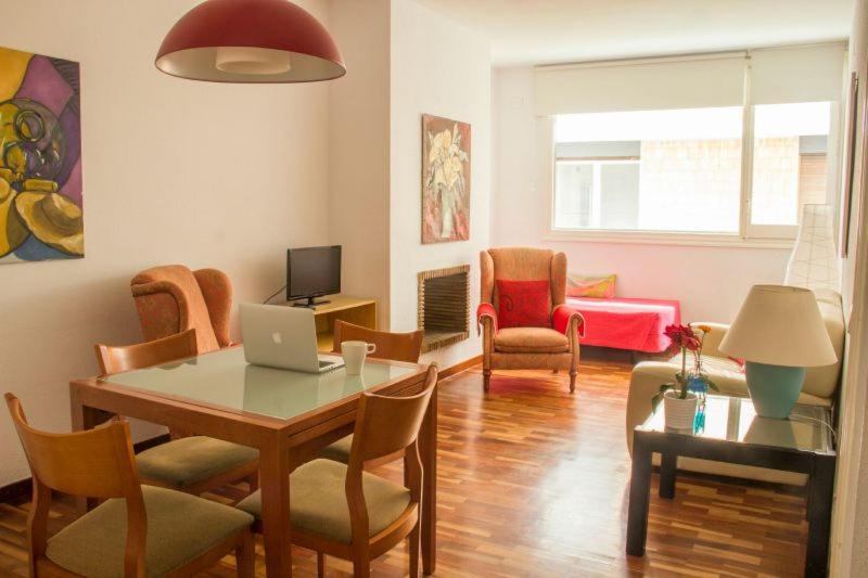 バルセロナにあるSweet BCN Three Bedroom Apartmentのリビングルーム(ノートパソコン、テーブル、椅子付)