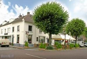 a white house with a tree in front of a street at Hotel Restaurant Hestia in Eijsden