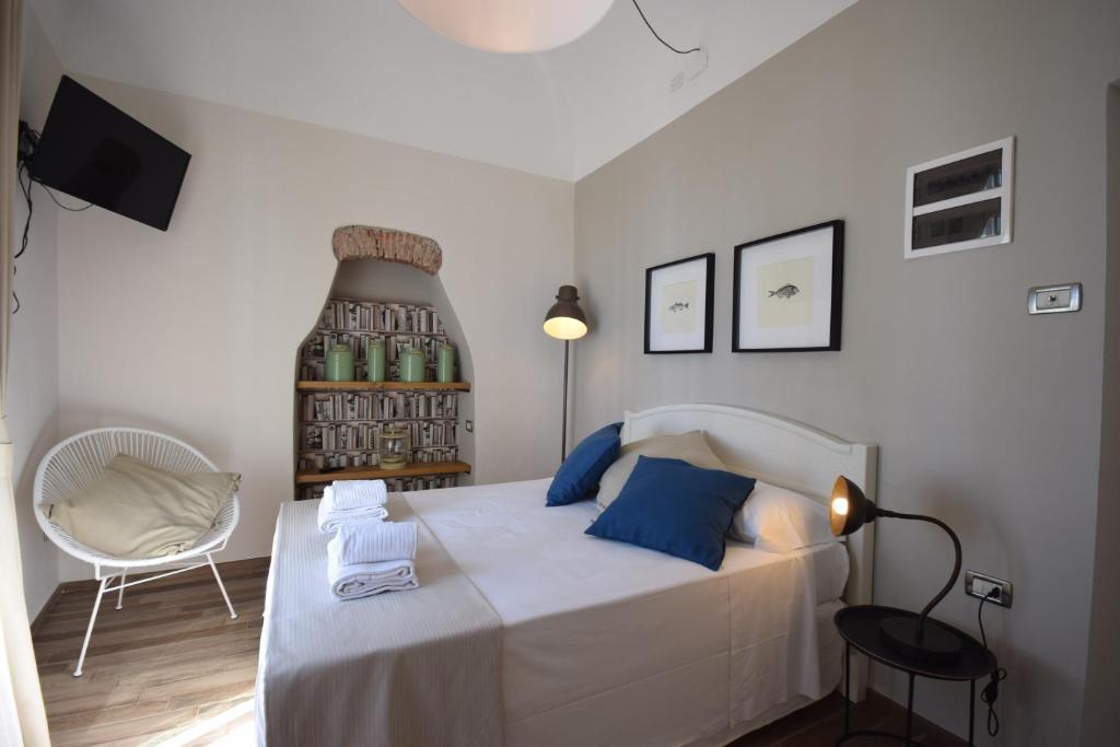 a bedroom with a bed with blue pillows and a chair at Locanda Fra Diavolo in Diano Marina