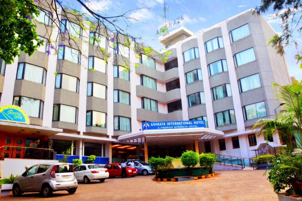 a large building with cars parked in front of it at Ashraya International Hotel in Bengaluru
