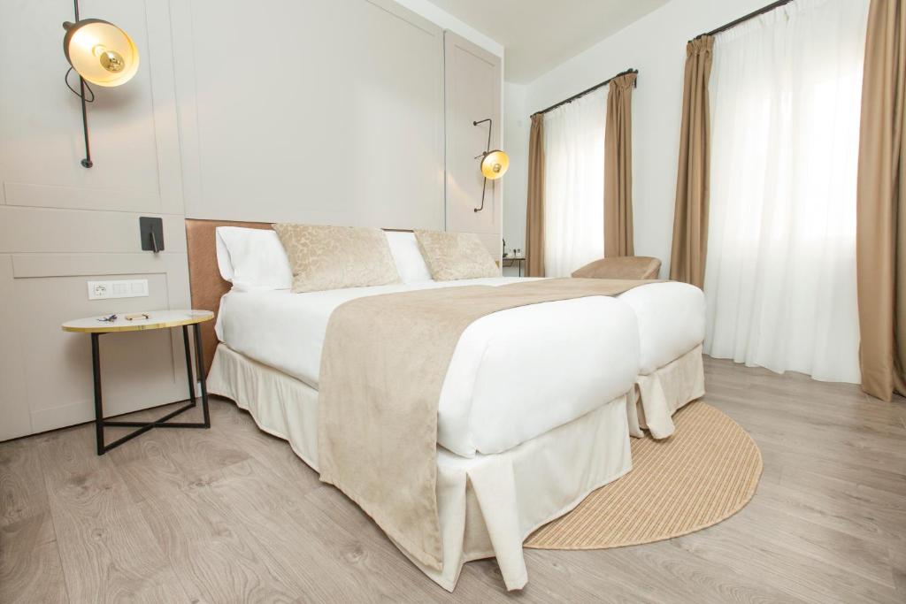 a bedroom with a large white bed and a table at ICON Rosetó in Palma de Mallorca