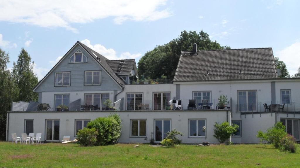 a large white house with chairs in front of it at Ferienwohnungen direkt am Schmollensee in Bansin