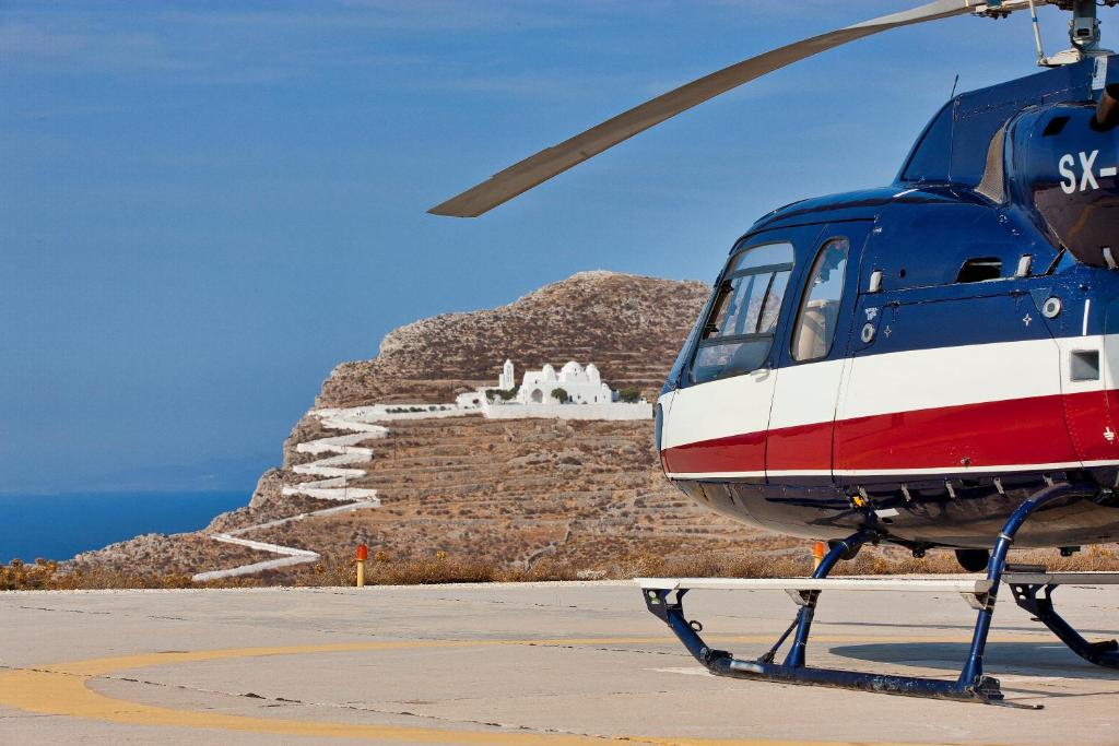 a helicopter parked on a runway in front of a mountain at ANEMI Folegandros in Karavostasi
