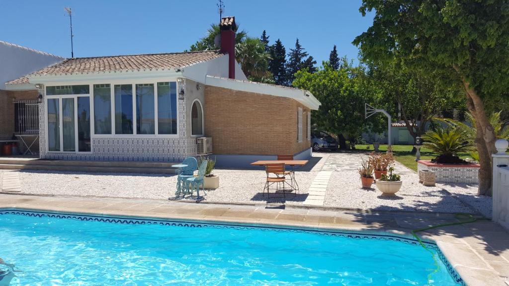 una casa con piscina frente a una casa en El Cortijo, en Chiclana de la Frontera