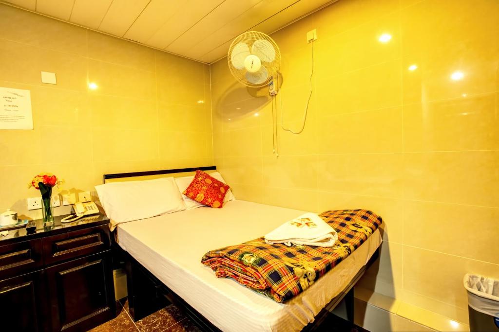 a small room with a bed and a fan at Nagaland Guesthouse in Hong Kong