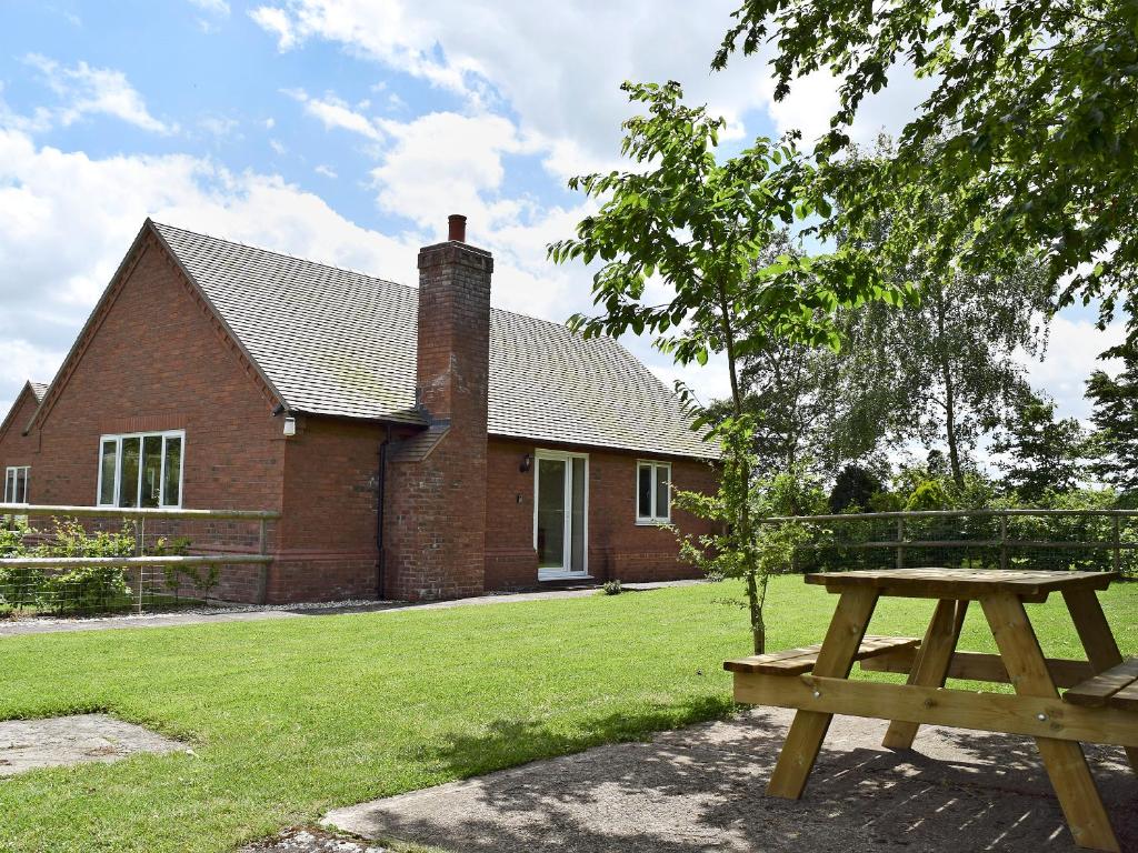 a picnic table in front of a brick house at Hornbeam Cottage in Malvern Wells