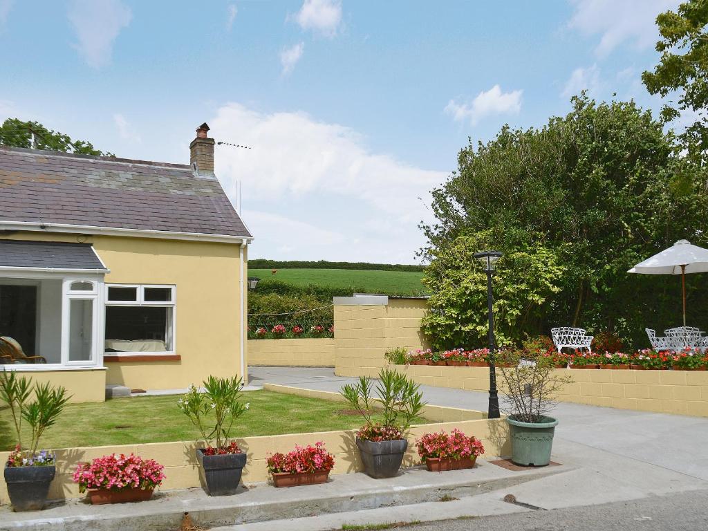 una casa gialla con piante in vaso in un cortile di Bont Cottage a Kidwelly