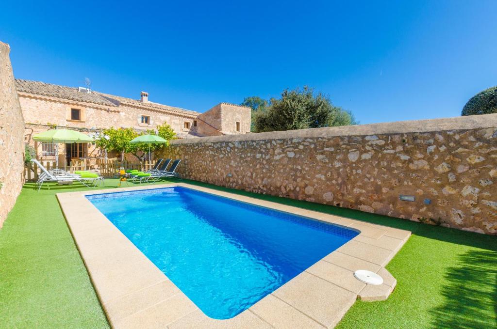 a swimming pool in a yard next to a stone wall at Finca Can Maria Costitx in Costitx