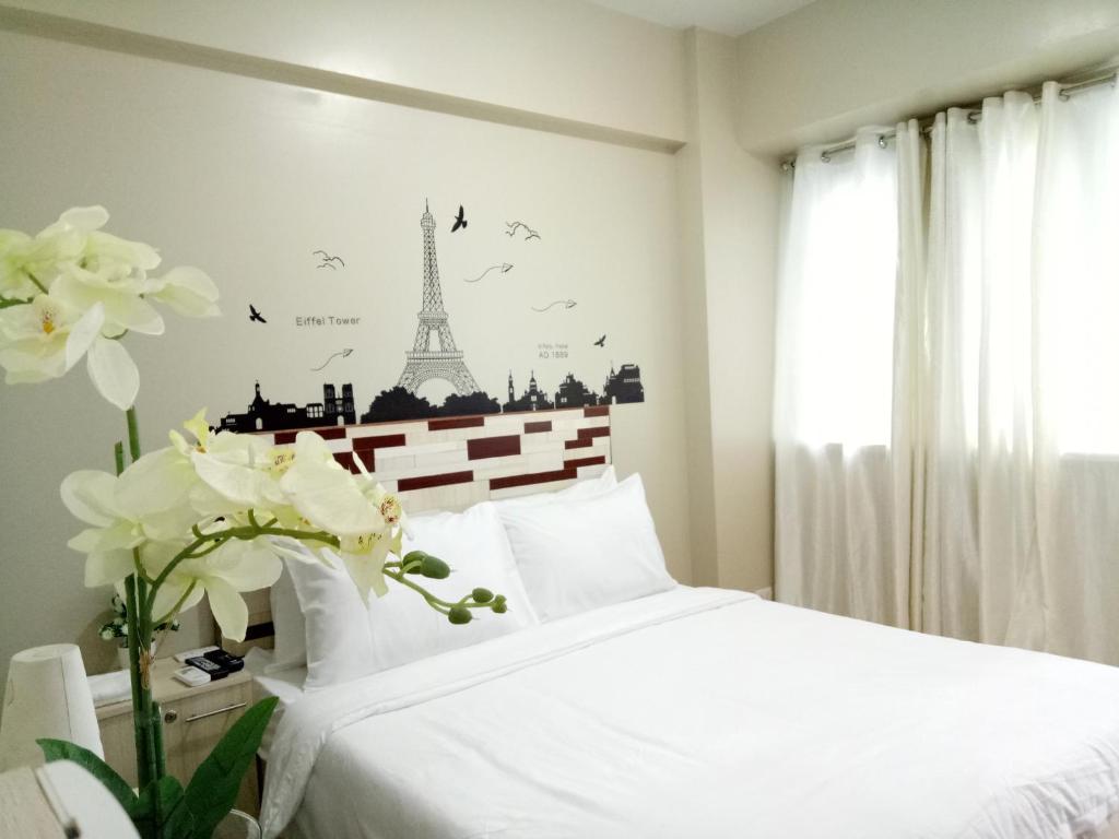 a bedroom with a white bed with the eiffel tower at NEW CONDO UNIT@PALMTREE VILLAS NEAR NAIA3 in Manila