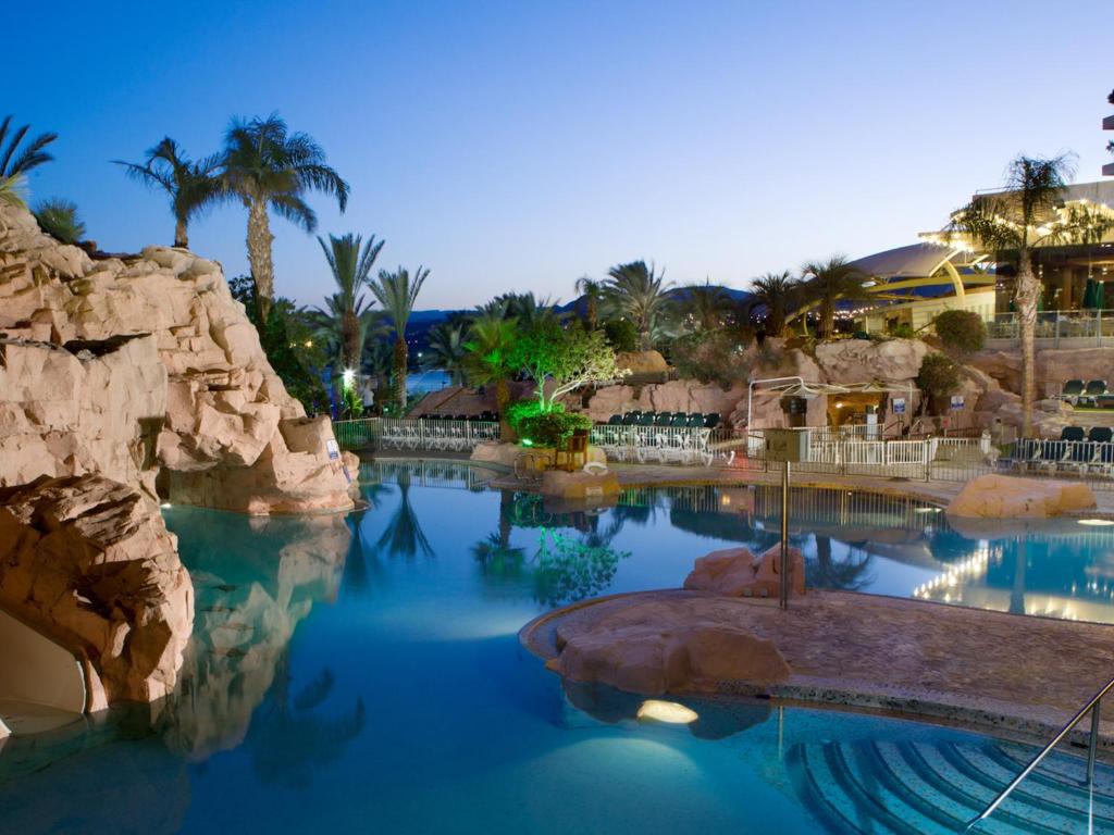 una piscina en un complejo con palmeras en Dan Eilat Hotel en Eilat