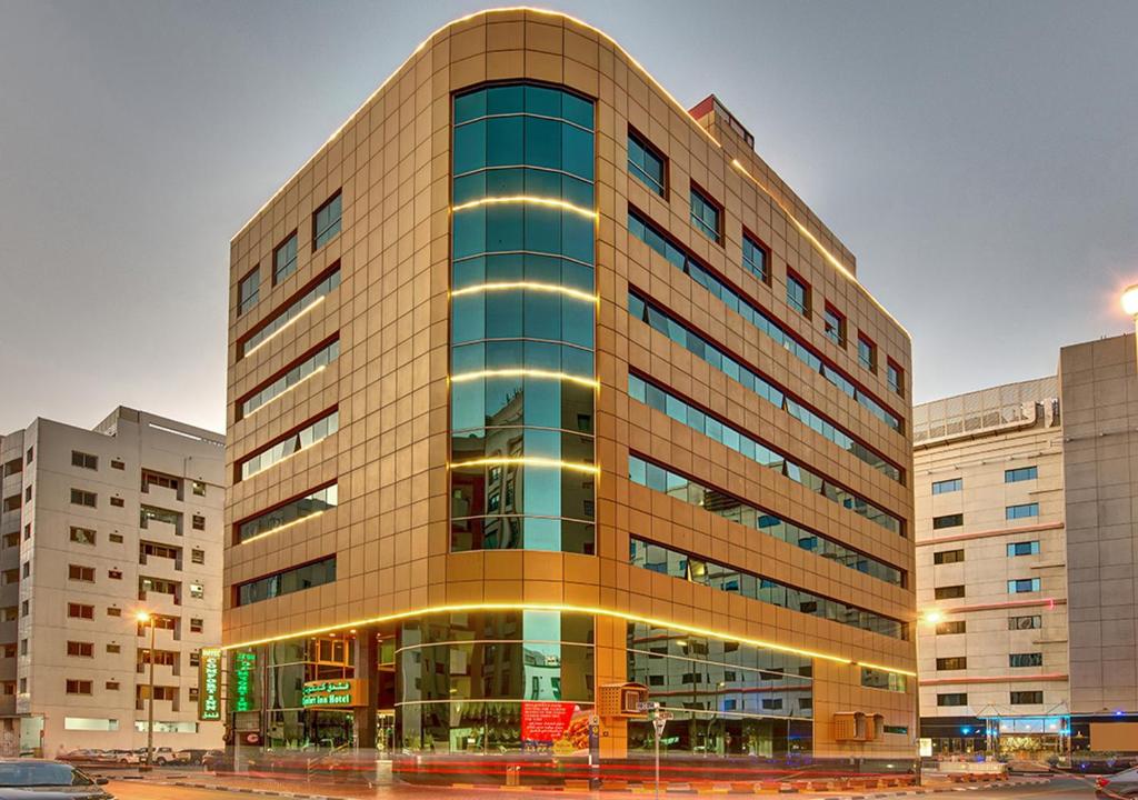 a large building with glass windows in a city at Comfort Inn Hotel Deira in Dubai