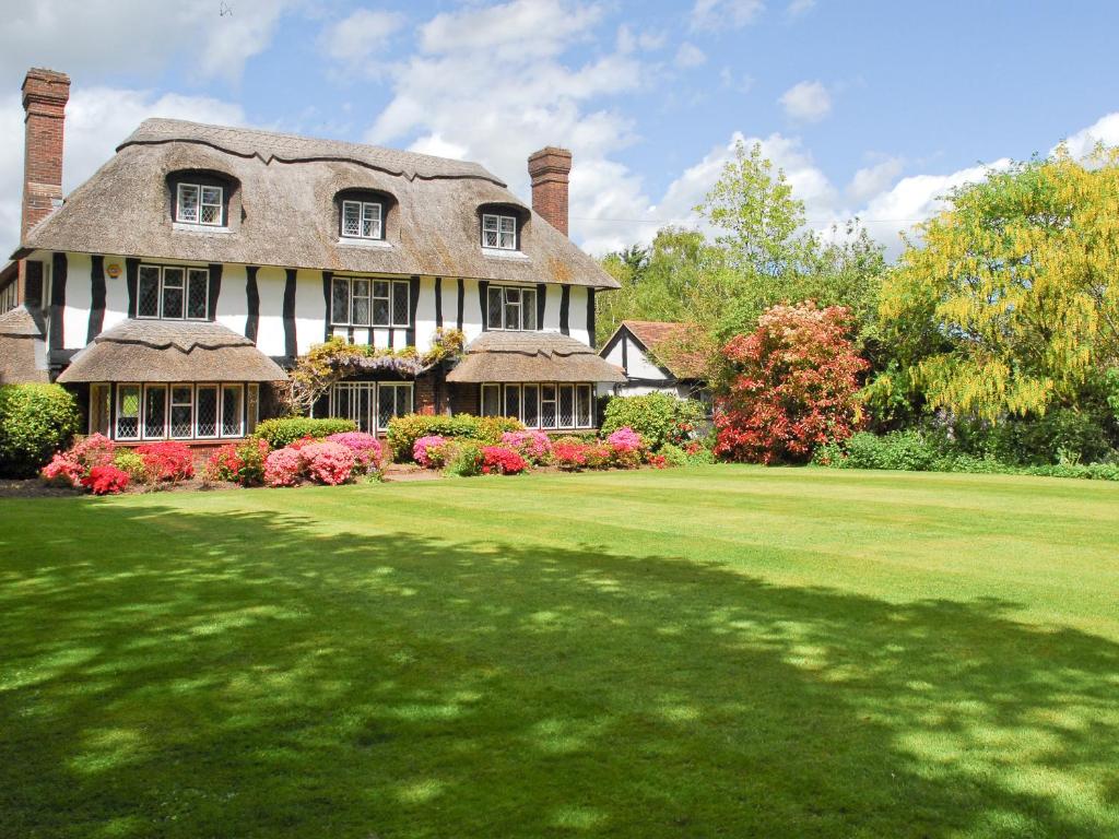 a large house with a thatched roof on a lawn at Silverland in Hordle