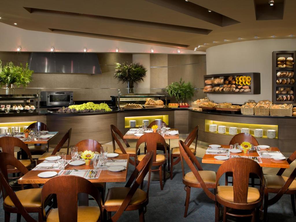 ein Restaurant mit Tischen und Stühlen und einer Küche in der Unterkunft Dan Eilat Hotel in Eilat